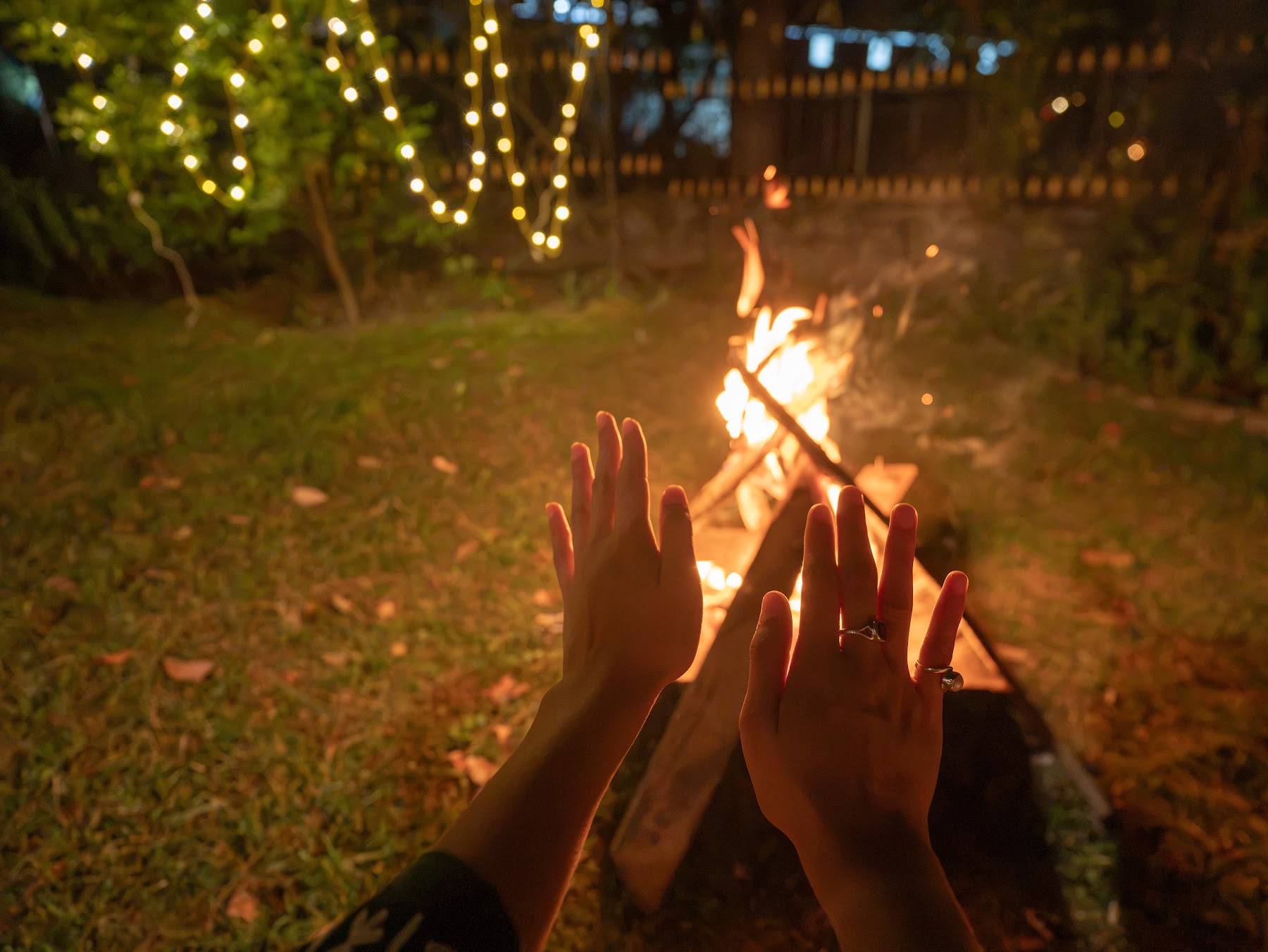 Warming hands at the bonfire under string lights